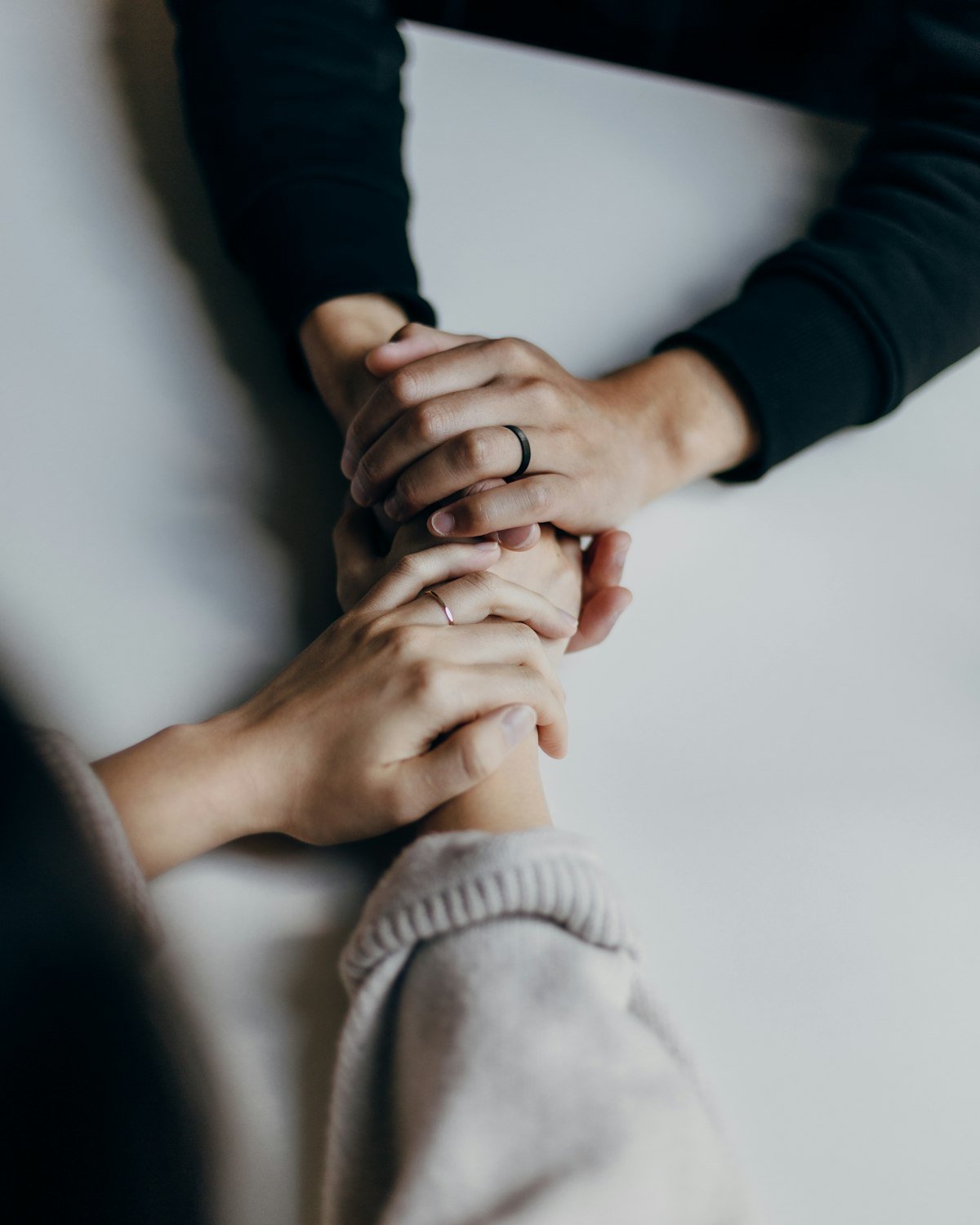 Two people sitting at a table, one holding the other's hands in reassurance